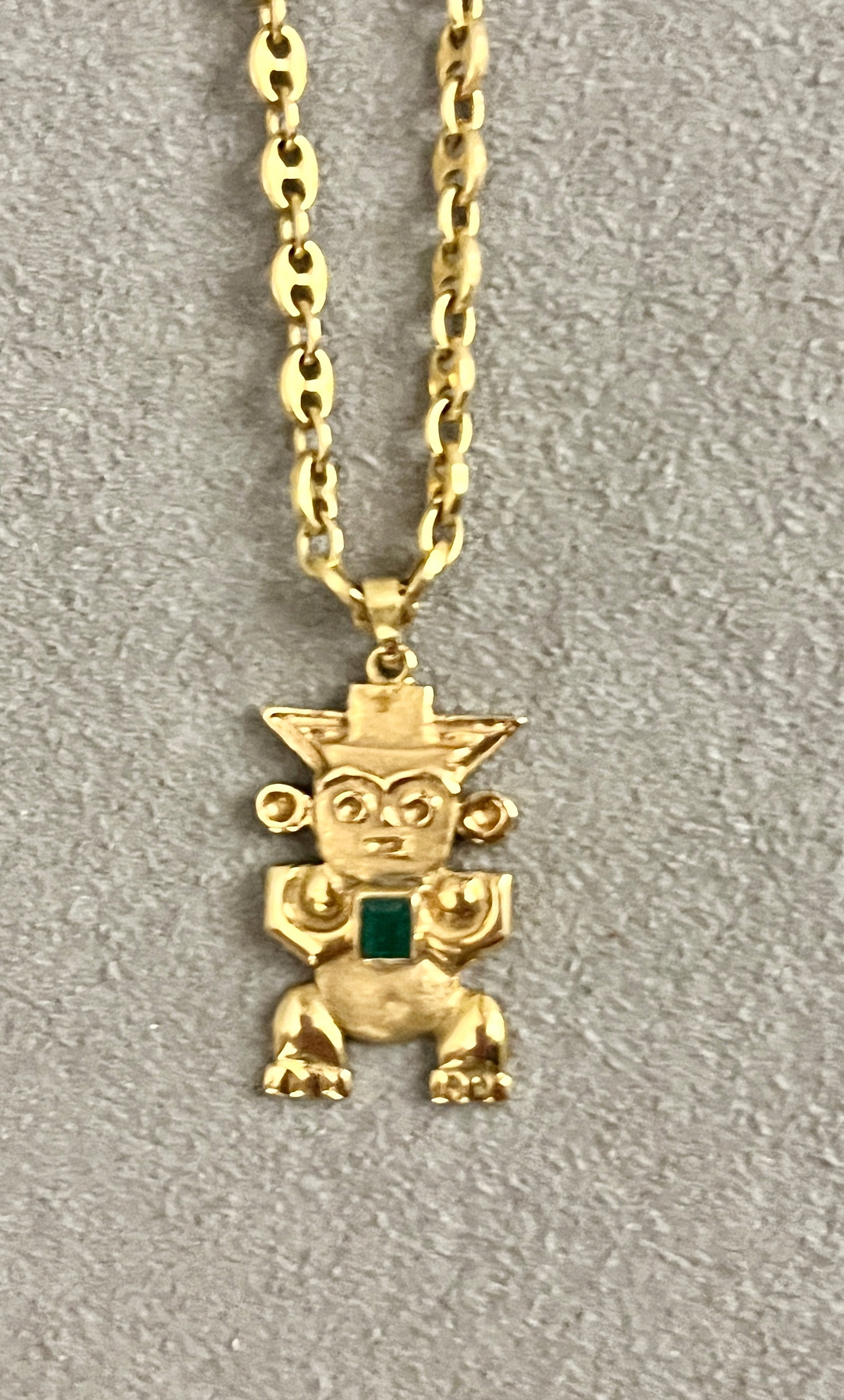 18K YELLOW GOLD PERUVIAN AZTEC FIGURE PENDANT SUSPENDED ON 18K FLEXIBLE GUCCI-LINK CHOKER CHAIN: 18K YELLOW GOLD PERUVIAN AZTEC FIGURE PENDANT SUSPENDED ON 18K FLEXIBLE GUCCI-LINK CHOKER CHAIN Figure mounted with bezel-set rectangular emerald. Pendant, L: 1 3/16". Chains, L: 16". Gross wt: 11 dwt