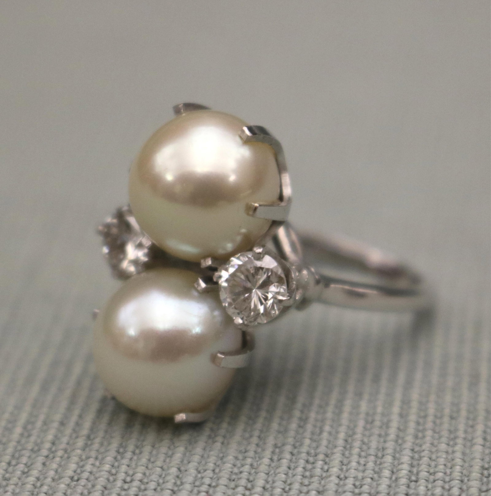 14K WHITE GOLD, AND DIAMOND AND CULTURED PEARL RING Pair of vertically-oriented white cultured: 14K WHITE GOLD, AND DIAMOND AND CULTURED PEARL RING Pair of vertically-oriented white cultured pearls of 10.5mm in diameter, centered by pair matched brilliant-cut round diamonds each weighing app. .5