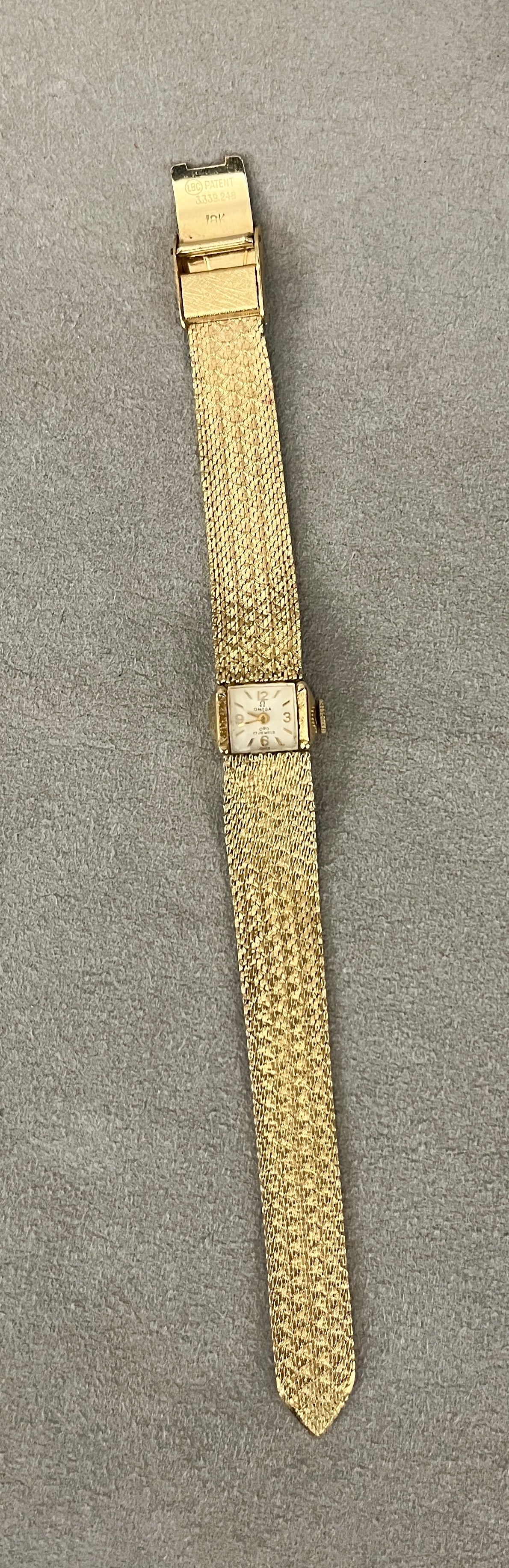 LADY'S 18K (750) YELLOW GOLD WRISTWATCH BY OMEGA Square case centering white gold face with Arabic: LADY'S 18K (750) YELLOW GOLD WRISTWATCH BY OMEGA Square case centering white gold face with Arabic numerals and bars for indices; tapering flexible strap constructed of tightly fitted links with overa