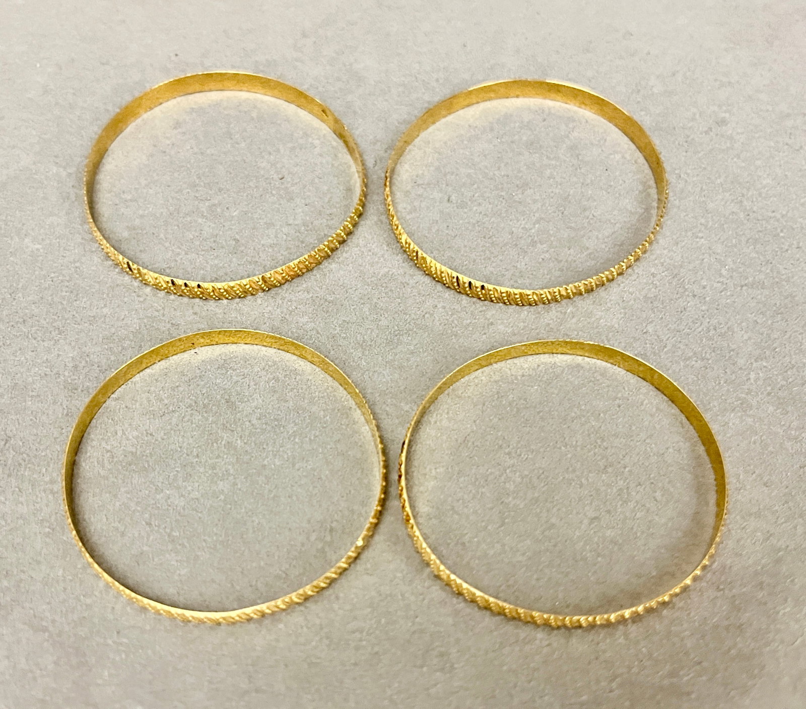 SET OF FOUR 21K YELLOW GOLD CIRCULAR SLIP-ON BANGLE BRACELETS Incised and beaded decoration. W: (1 of 2)