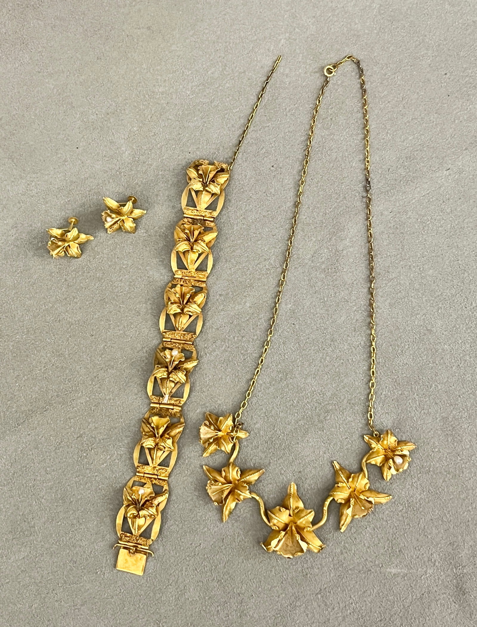 THREE-PIECE SUITE 18K TEXTURED YELLOW GOLD ORCHID DESIGN JEWELRY Including choker, flexible: THREE-PIECE SUITE 18K TEXTURED YELLOW GOLD ORCHID DESIGN JEWELRY Including choker, flexible panel-link bracelet and pair screw-back earrings. Choker has five graduated orchid blossoms centered by oval