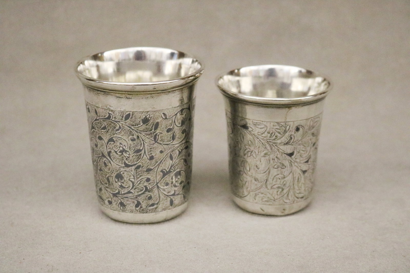 TWO RUSSIAN NIELLO SILVER (84-FINE) CUPS 19th century - .: TWO RUSSIAN NIELLO SILVER (84-FINE) CUPS 19th century One, 1857; other with rubbed marks. Wide frieze panels of trailing vine decoration. Taller, H: 3 1/4 in. Wt. 5 troy oz.