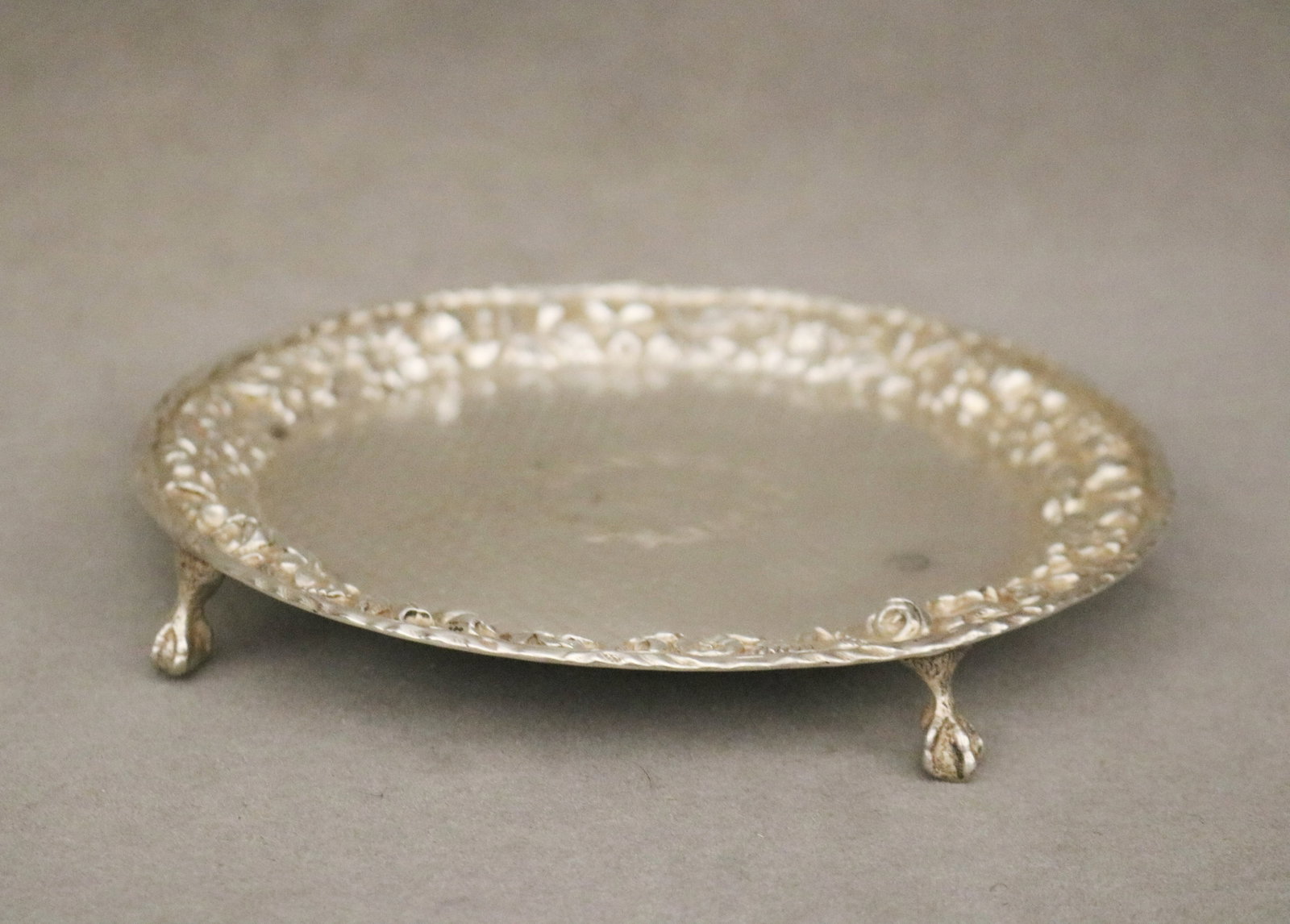 LATE 19TH CENTURY S. KIRK & SON CO. STERLING SILVER FOOTED CIRCULAR SALVER - .: LATE 19TH CENTURY S. KIRK & SON CO. STERLING SILVER FOOTED CIRCULAR SALVER Floral repousse border; diapered ground centers wreath reserve with monogram; raised on three bird claw-and-ball feet. D: 6