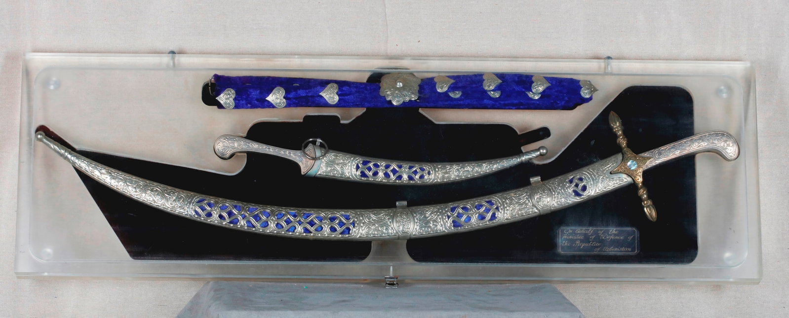 PRESENTATION SHAMSHIR SWORD, GIFT FROM THE MINISTRY OF DEFENSE OF THE REPUBLIC OF UZBEKISTAN, IN: PRESENTATION SHAMSHIR SWORD, GIFT FROM THE MINISTRY OF DEFENSE OF THE REPUBLIC OF UZBEKISTAN, IN FITTED DISPLAY CASE 20th century Ornate ceremonial shamshir (curved Central Asian sword) with a matchin