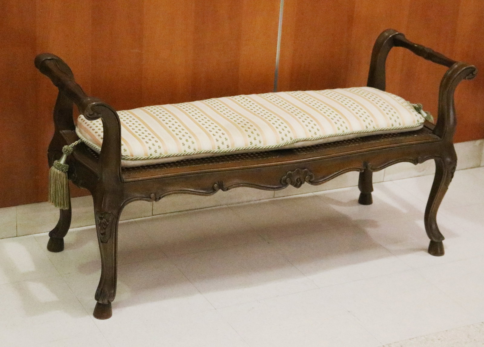 LOUIS XV STYLE FRUITWOOD, CANE-SEAT, OPEN-ARM BENCH - H: 21 7/8 in.; L:40 1/2 in.; D: 16 1/2 in..: LOUIS XV STYLE FRUITWOOD, CANE-SEAT, OPEN-ARM BENCH Serpentine apron with carved shell motif; cabriole legs raised on hoof feet; separate seat cushion H: 21 7/8 in.; L:40 1/2 in.; D: 16 1/2 in.