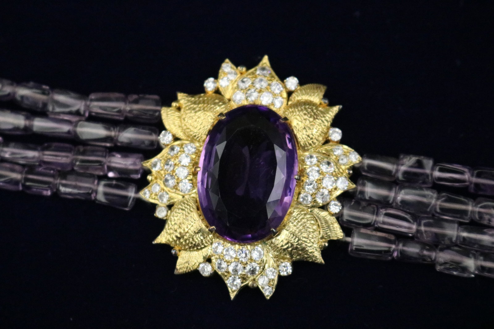 AMETHYST AND WHITE SAPPHIRE FLORAL DESIGN FOUR-STRAND COLLAR CHOKER - .: AMETHYST AND WHITE SAPPHIRE FLORAL DESIGN FOUR-STRAND COLLAR CHOKER Oval amethyst weighing approximately 15 ct., centered by textured gilt metal petals set with numerous round white sapphires; form st