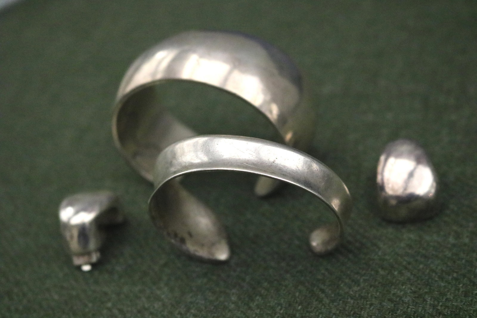 THREE ITEMS STERLING SILVER JEWELRY OF CONTEMPORARY SCULPTED DESIGN - Wt. 4 oz. 6 dwt..: THREE ITEMS STERLING SILVER JEWELRY OF CONTEMPORARY SCULPTED DESIGN Including open-end oval cuff bracelet, W: 1 3/16"; tapering, graduated open-end oval cuff bracelet, L: 1. Wt: 4 oz. 6 dwt.; and pair