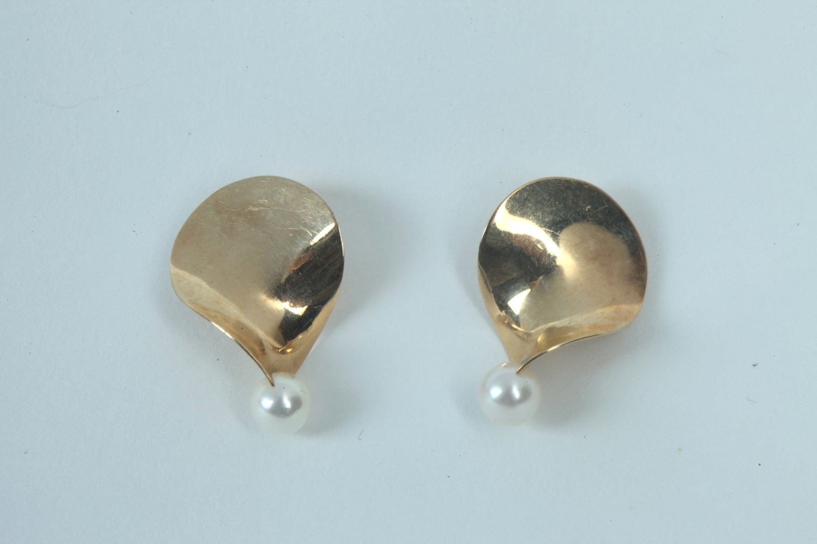 PAIR SIGNED TIMOTHY GRANNIS 14K BRIGHT-POLISHED YELLOW GOLD AND CULTURED PEARL POST-BACK EARRINGS -: PAIR SIGNED TIMOTHY GRANNIS 14K BRIGHT-POLISHED YELLOW GOLD AND CULTURED PEARL POST-BACK EARRINGS Pearl post-back earrings. Each of stylized twisted leaf design with 5.35 mm pearl. L: 7/8". Gross WT: 