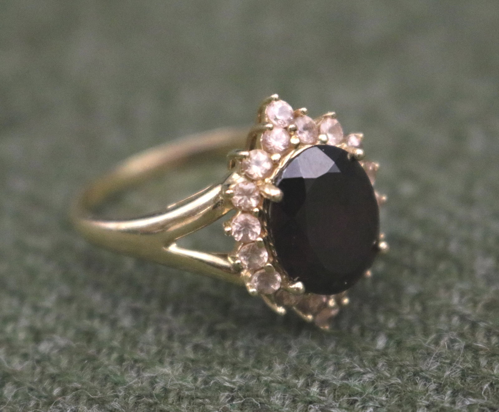 14K YELLOW GOLD, GARNET AND WHITE SAPPHIRE RING - Ring size: 9. Gross wt: 3 dwt..: 14K YELLOW GOLD, GARNET AND WHITE SAPPHIRE RING Oval garnet surrounded by 18 matched round white sapphires. Ring size: 9. Gross wt: 3 dwt.
