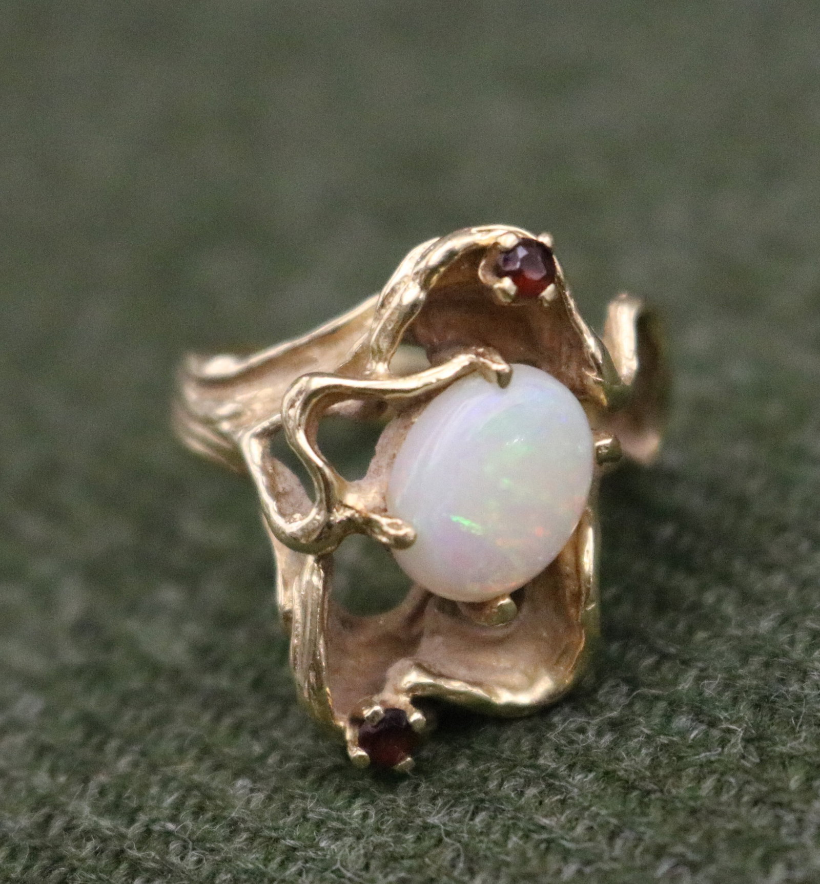 CONTEMPORARY DESIGN 14K YELLOW GOLD, PRECIOUS WHITE OPAL AND GARNET ASYMMETRICAL OPENWORK RING - .: CONTEMPORARY DESIGN 14K YELLOW GOLD, PRECIOUS WHITE OPAL AND GARNET ASYMMETRICAL OPENWORK RING White opal oval cabochon held by four prongs and vertically centered in naturalistically textured setting