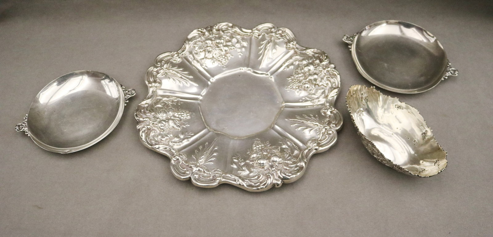 FOUR ITEMS STERLING SILVER TABLEWARE - Wt. 30.6 troy oz..: FOUR ITEMS STERLING SILVER TABLEWARE Including vintage Tiffany & Co. boat-shape bonbon dish with relief cherub decoration, L: 6 1/4 in. pair Durham Co. shallow circular bonbon dishes, D: 5 5/8 in.; an
