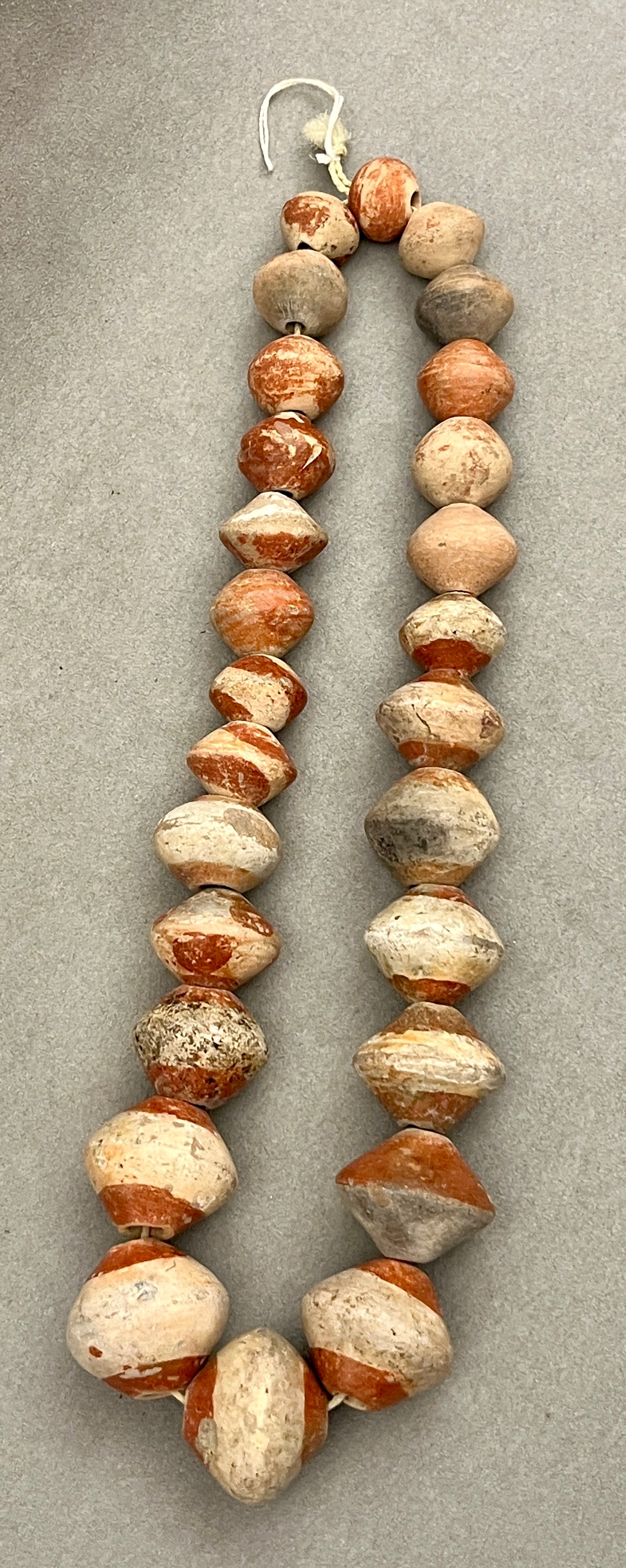 PRE-COLUMBIAN BICONICAL CERAMIC BEAD NECKLACE, TERRACOTTA AND BUFF SLIP - length: 26 inches.: PRE-COLUMBIAN BICONICAL CERAMIC BEAD NECKLACE, TERRACOTTA AND BUFF SLIP Strand of large biconical / rounded ceramic beads in mottled terracotta, buff, and grey tones, each with a two-tone slip finish;