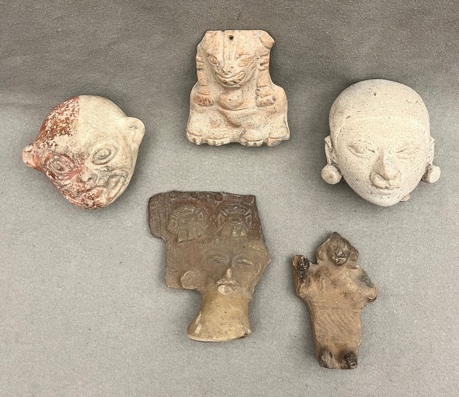 GROUP OF FIVE PRE-COLUMBIAN POTTERY FRAGMENTS, INCLUDING HEAD FRAGMENTS AND A SEATED FIGURE - All: GROUP OF FIVE PRE-COLUMBIAN POTTERY FRAGMENTS, INCLUDING HEAD FRAGMENTS AND A SEATED FIGURE Group of five earthenware Pre-Columbian fragments comprising two large head fragments with elongated feature