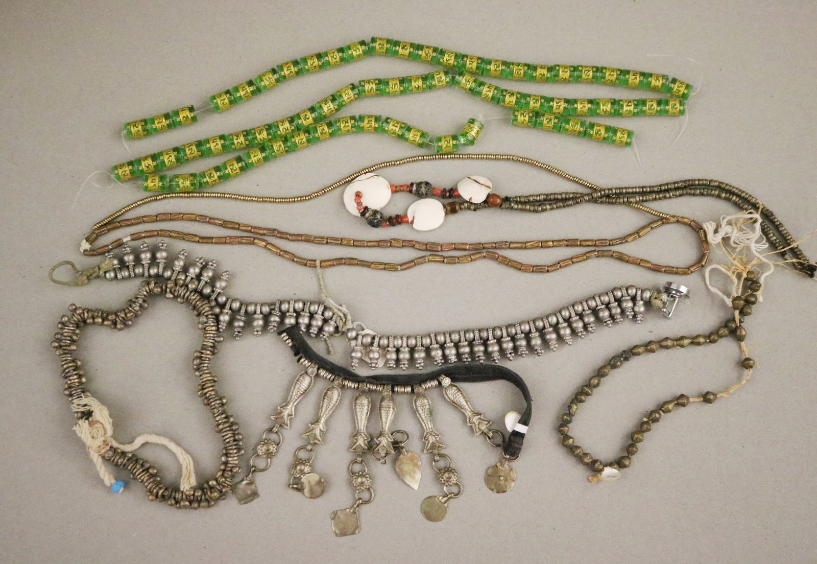 GROUP OF ETHNIC NECKLACES AND BEADED STRANDS; SILVER-TONE FISH-CHARM NECKLACE, TRADE BEAD STRANDS &: GROUP OF ETHNIC NECKLACES AND BEADED STRANDS; SILVER-TONE FISH-CHARM NECKLACE, TRADE BEAD STRANDS & TRIBAL BEADWORK A varied lot of tribal and ethnic-style necklaces and beaded strands from a jewelry 