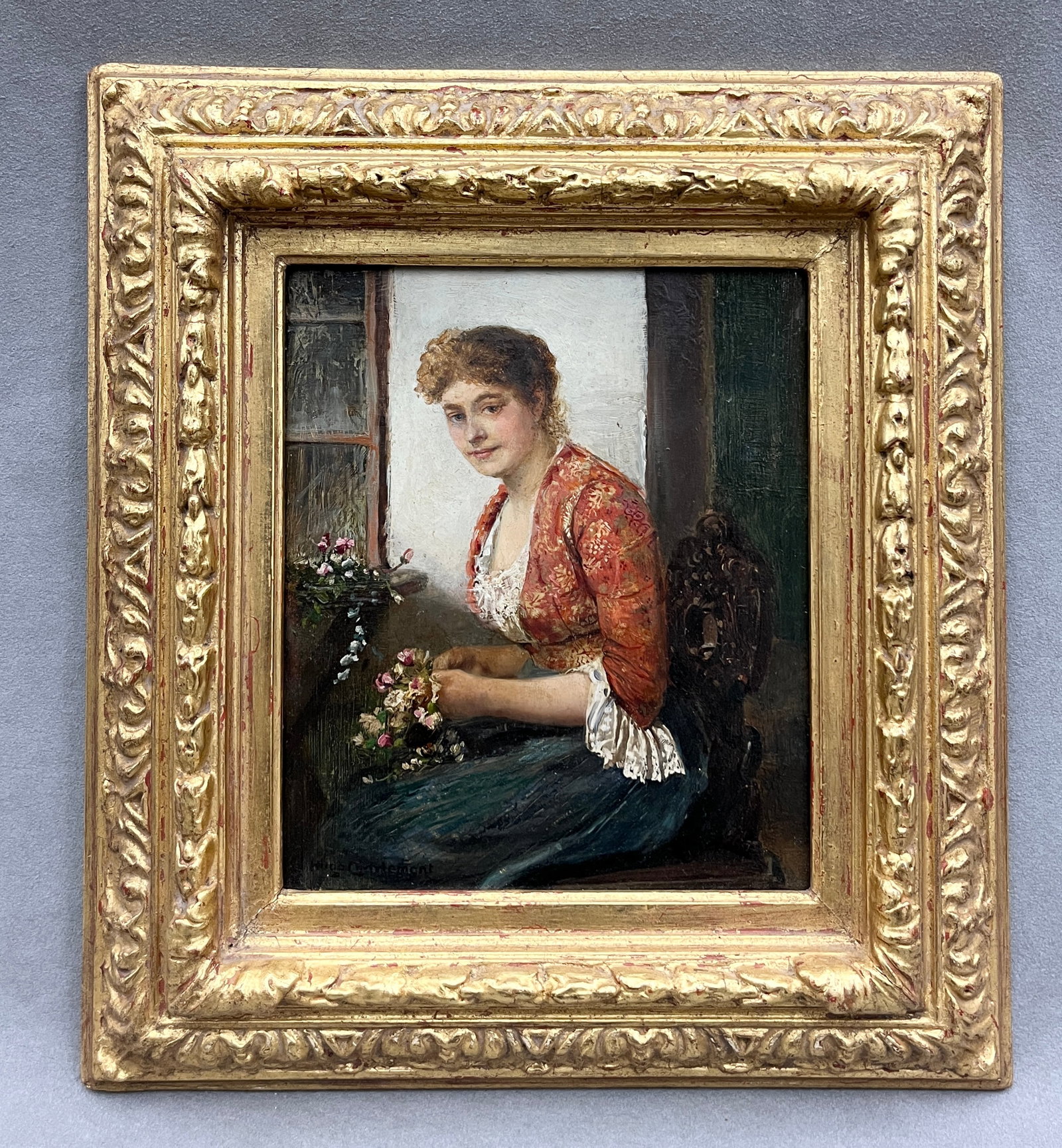 HUGO CHARLEMONT (Austrian, 1850-1939). The Flower Arranger, Oil on board: HUGO CHARLEMONT Austrian, 1850-1939 The Flower Arranger Oil on board Signed lower left. Artwork depicting a rosy-cheeked young woman seated by a window arranging a bouquet of pink and white flowers, w