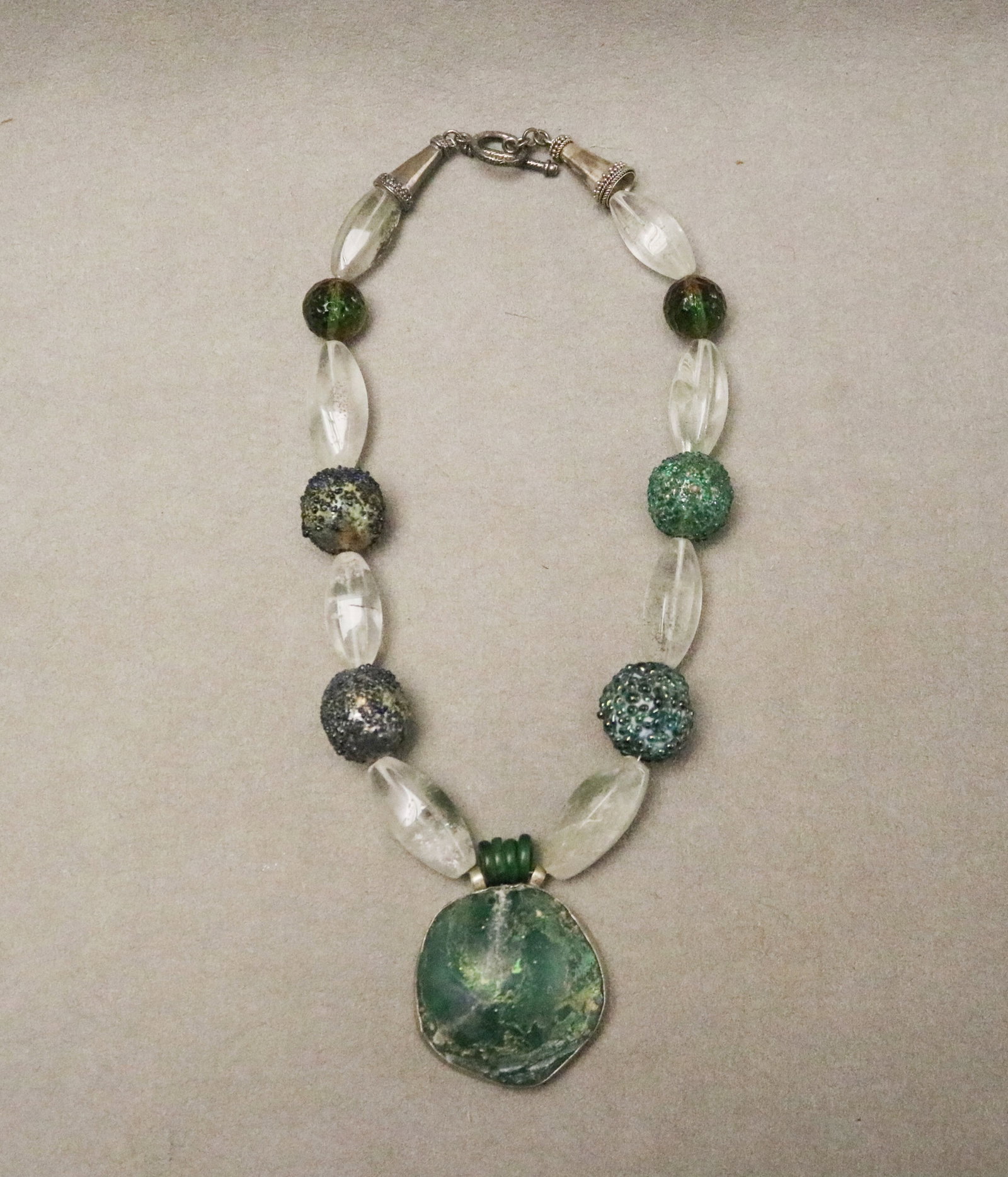 CONTEMPORARY ARTISAN-CRAFTED NECKLACE BY ROSALEE COHEN DAVISON WITH ROMAN GLASS PENDANT - L: app. 16: CONTEMPORARY ARTISAN-CRAFTED NECKLACE BY ROSALEE COHEN DAVISON WITH ROMAN GLASS PENDANT Bezel-set Roman glass fragment, H: 1 5/8 in., accented by frosted oval quartz and spherical beads in the style o