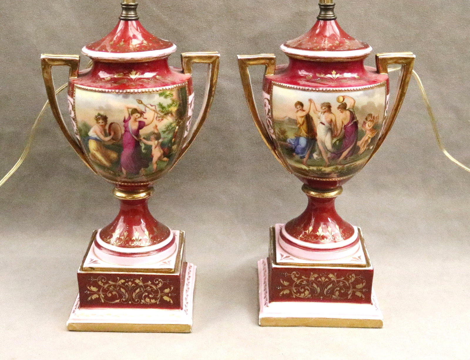 PAIR ROYAL VIENNA POLYCHROME PAINTED PORCELAIN TWO-HANDLE VASES MOUNTED AS TWO-LIGHT TABLE LAMPS: PAIR ROYAL VIENNA POLYCHROME PAINTED PORCELAIN TWO-HANDLE VASES MOUNTED AS TWO-LIGHT TABLE LAMPS late 19th century Frieze decoration of Neoclassical figures in landscape on magenta and pink grounds wi
