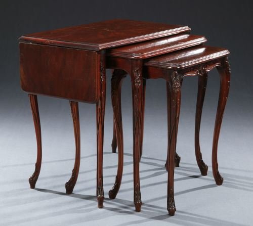 THREE LOUIS XV STYLE MAHOGANY NESTING TEA TABLES,: THREE LOUIS XV STYLE MAHOGANY NESTING TEA TABLES, circa 1900. The largest table with a rectangular top with twin flaps, all raised on foliate and floral-carved cabriole legs with scroll feet - 24 1/2