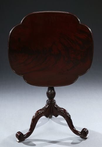 A GEORGE III FIGURED MAHOGANY TILT-TOP TEA TABLE,: A GEORGE III FIGURED MAHOGANY TILT-TOP TEA TABLE, circa 1760-1770. In the manner of Thomas Chippendale. The cover-leaf top above a fluted and acanthus-carved baluster standard on a cabochon and foliat