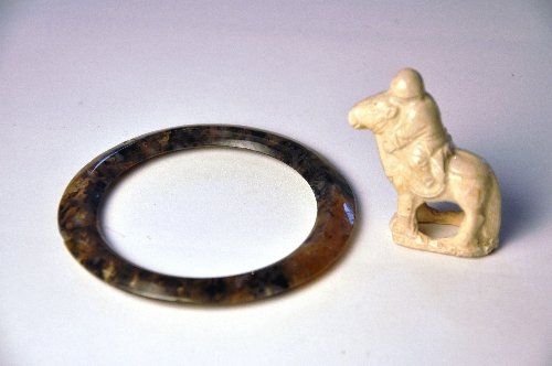 A miniature C13th/14th Yuan Dynasty Chinese straw glaze: A miniature C13th/14th Yuan Dynasty Chinese straw glazed figure on a horse Height 5 cm and an agate Chinese bangle Han Dynasty Diameter 10.5 cm