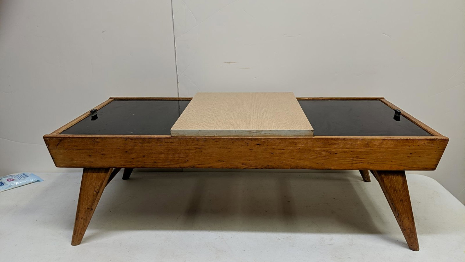 Mid Century Modern oak coffee table: retractable door on top. each side will slide under the raised center 20" W x 42 " L x 14 1/4" T
