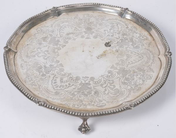 A George III silver shaped circular salver by Robe: A George III silver shaped circular salver by Robert Jones & John Scofield, London 1776, with a beaded and foliate rim, engraved with foliate swags and on three claw and ball feet, 23.5cm diameter