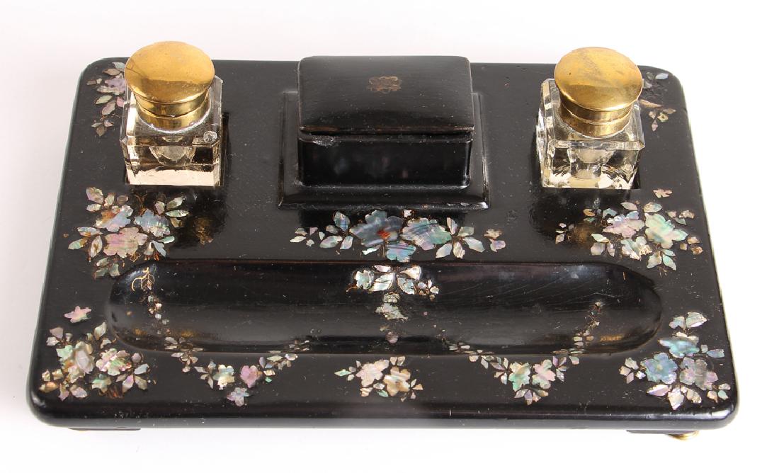Papier Mache Mother of Pearl Ink Stand: Papier mache with mother of pearl inlay, with two glass and brass inkwells, measuring 10 by 7 inches. Provenance: East End Galleries, Michael Malley.