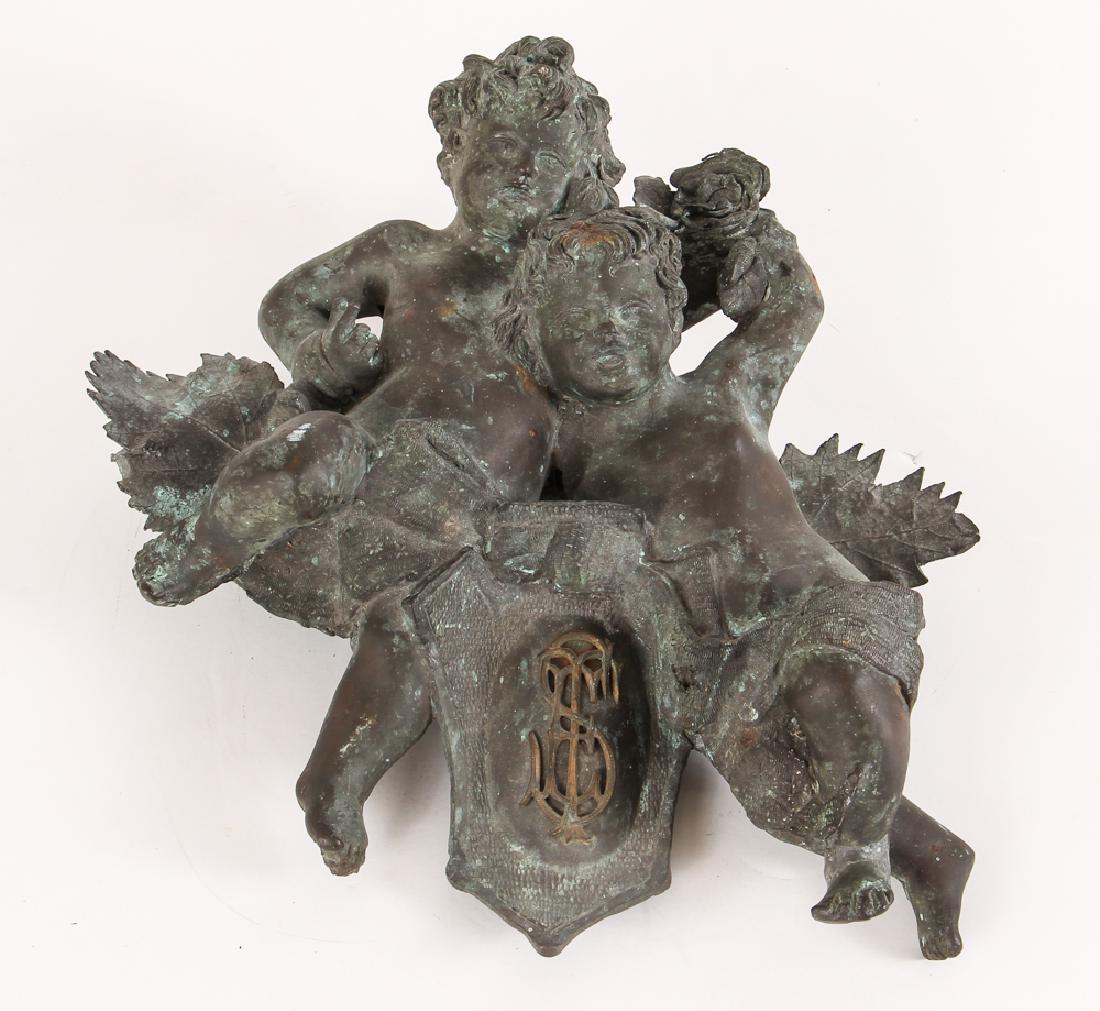 Bronze Architectural Wall relief of Puttis: Two entwined bronze Puttis reveling in nature, Bronze relief sculpture in high relief with decorative cartouche of conjoined initials, 13.5 x 14.5 x 3 inches, Provenance: Ruth Frank Collection