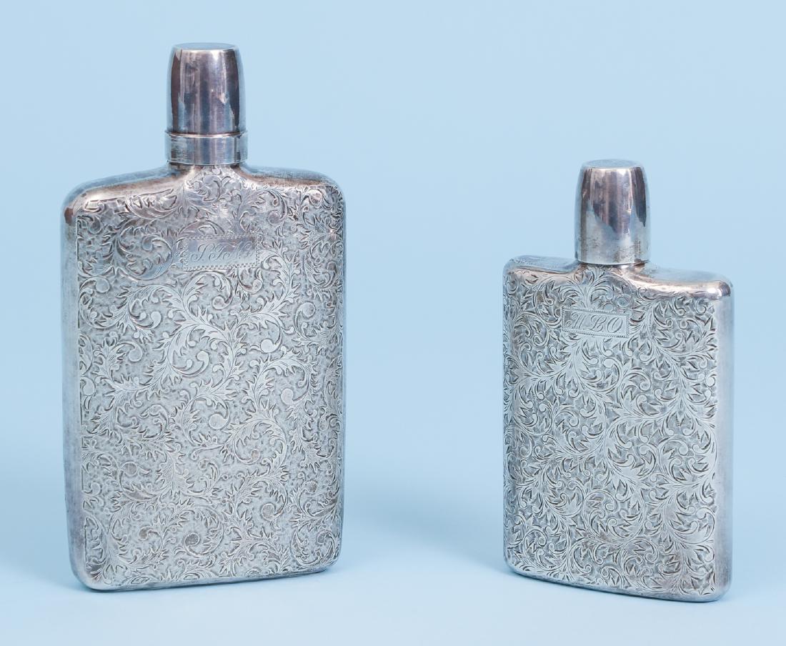 Two Highly Engraved His and Hers Silver Flasks: Two highly flasks, "his and hers" sizes, highly engraved with floral scroll themed bright work, larger flask opens to access an additional shot glass, 7 and 5.5 inches respectively, with marks for 950