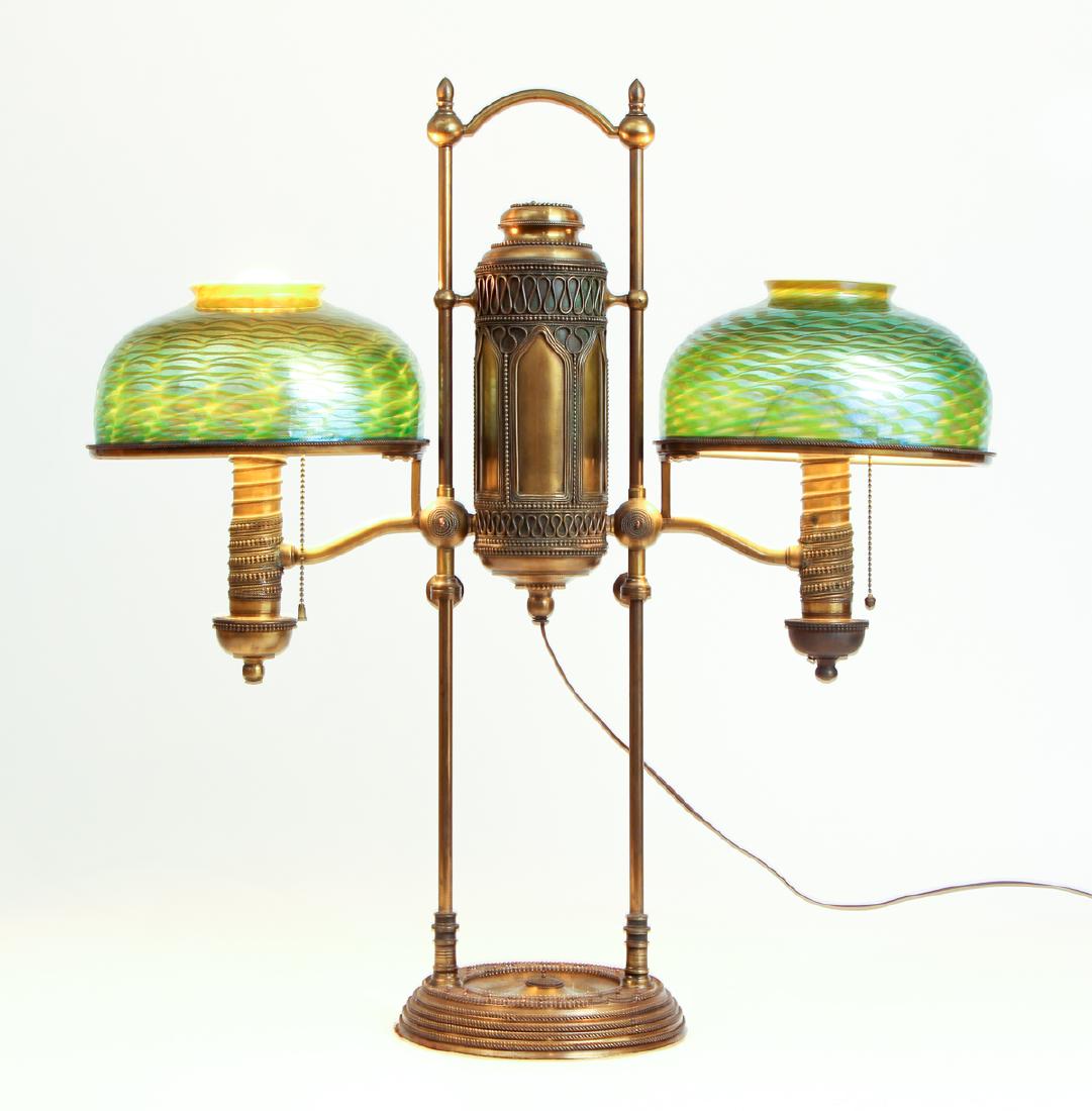 Tiffany Studios Double Student Lamp: Tiffany Studios double student lamp, the bronze base featuring wire beading decoration in an arabesque style, measuring 29 by 28 inches, adjustable, with two damascene shades, etched with fitter numbe