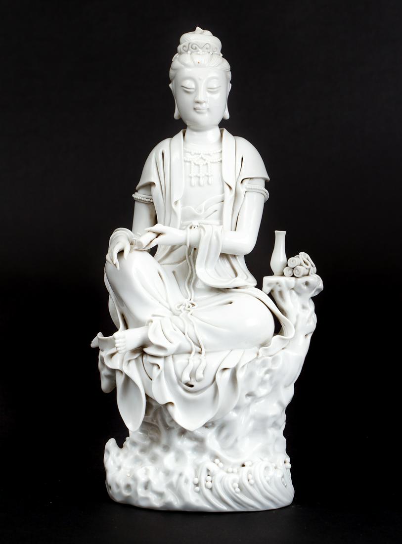 Blanc de Chine Guanyin Chinese Porcelain: Blanc de Chine Guanyin (Avalokitesvara), Goddess of Mercy in Buddhism, seated on a high rock holding a scroll, above foaming waves next to a short trunk supporting a vase and three further scrolls. Un
