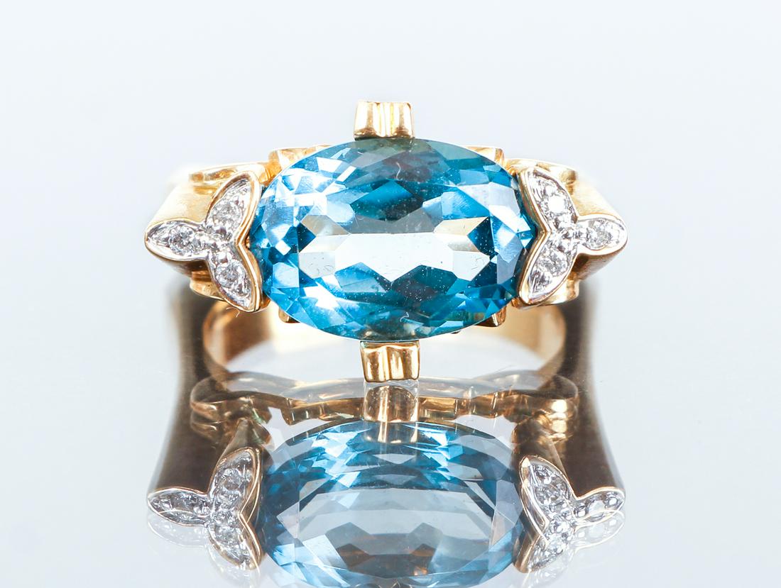 14K Gold and Aqua Ring: 14K gold and aquamarine ring. The yellow gold ring is set with a 3.5 carat multi-faceted oval cut aquamarine at its center. The center mount and shoulders are decorated with diamond set floral cutwork