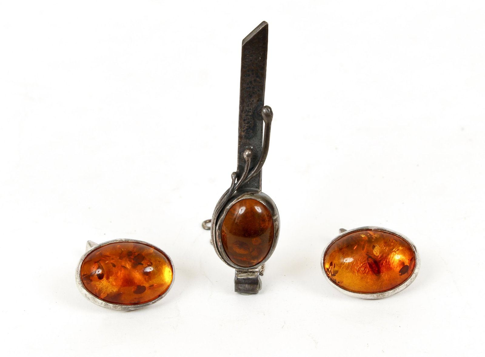 Sterling Amber Cuff Links and Tie Clip Set: Sterling and amber cufflink and tie clip set. Large polished amber is bezel set in sterling mountings. The cuff links measure 1" long, 3/4" wide, marked 925. The tie clip is hand hammered. Tie clip is