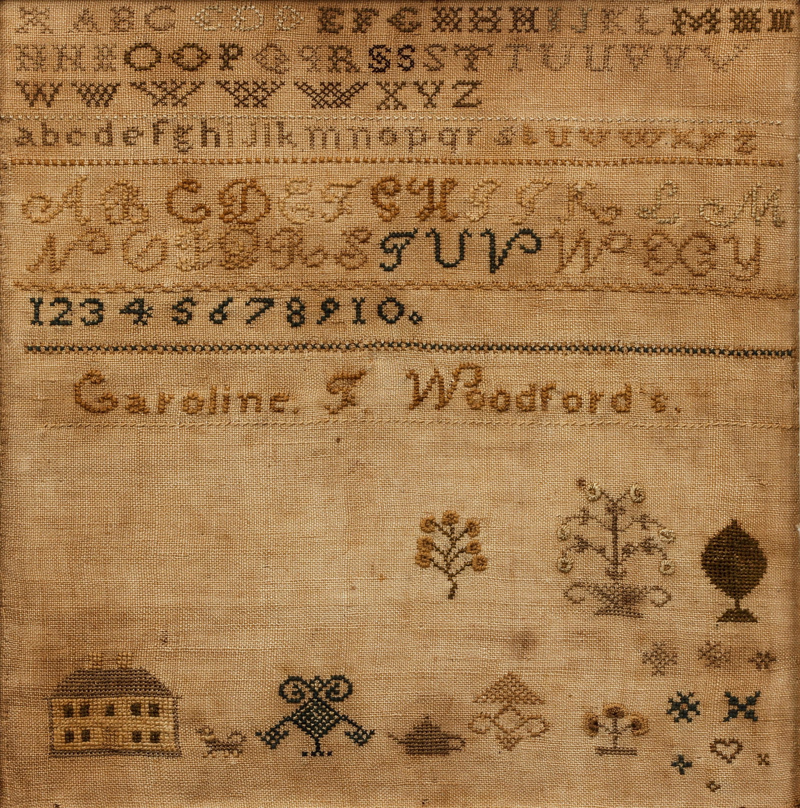 19th century Alphabet Sampler Woodford: Alphabet Sampler of Caroline Woodford, undated, 19th century, also includes numbers and images of a house, plants and assorted decorations. 10.25 x 10 inches, in a wooden frame.