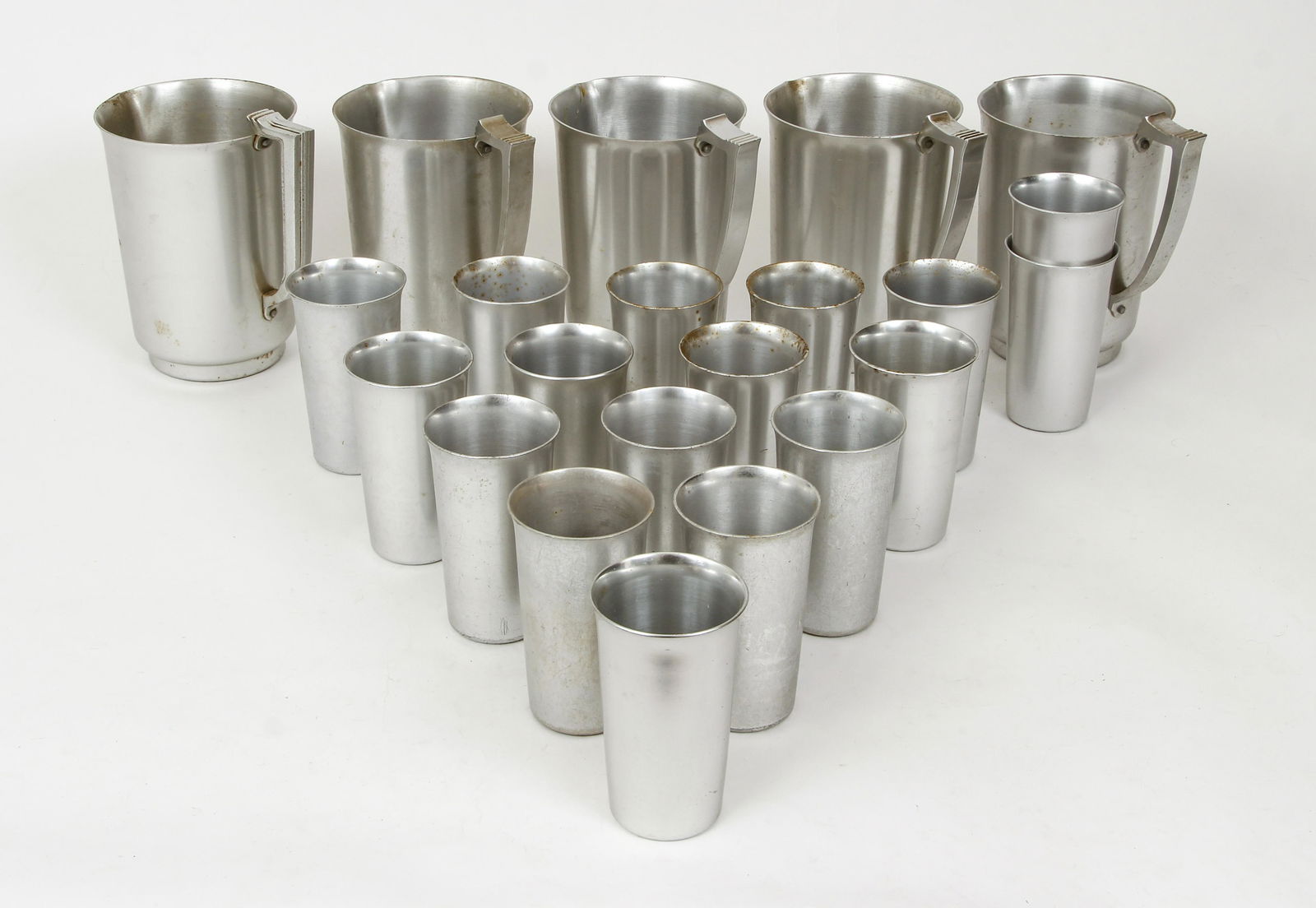 22pc Kensington Ware Mayfair Pitchers and Cups: 22 piece lot of Kensington Ware, aluminum, 5 water pitchers in the Mayfair pattern and 17 cups, each one etched on base, pitchers 7.75 inches tall, cups 5.25 inches tall, classic Art Deco design.
