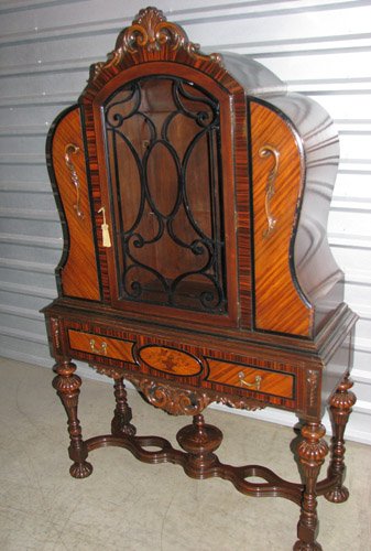 Renaissance Revival Elaborately Carved Faux Burl C: Artist: Rockford Excel Manufacturer Title: Elaborately Carved Faux Burl China Display Highboy Cabinet with torchiere stretcher, floral veneer inlay, glass front, swag embellishment, pod feet, shell cr