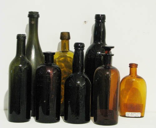 Eight Antique Brown Glass Bottles: Eight Antique Brown Glass Bottles including whiskey flask with star decoration glass tallest measures: 12 inches high Provenance: The James J. White Collection