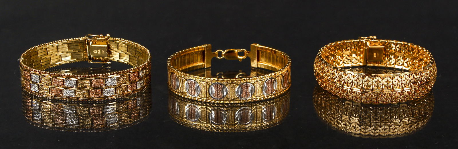 3 Italian Gold Plate Multi-Tone Bracelets: 3 Italian gold plate multi-tone bracelets. The first bracelet is comprised of multiple hinged panels finished with engraved surface patterns and jewel cut rings. The interior of the rings is colored i