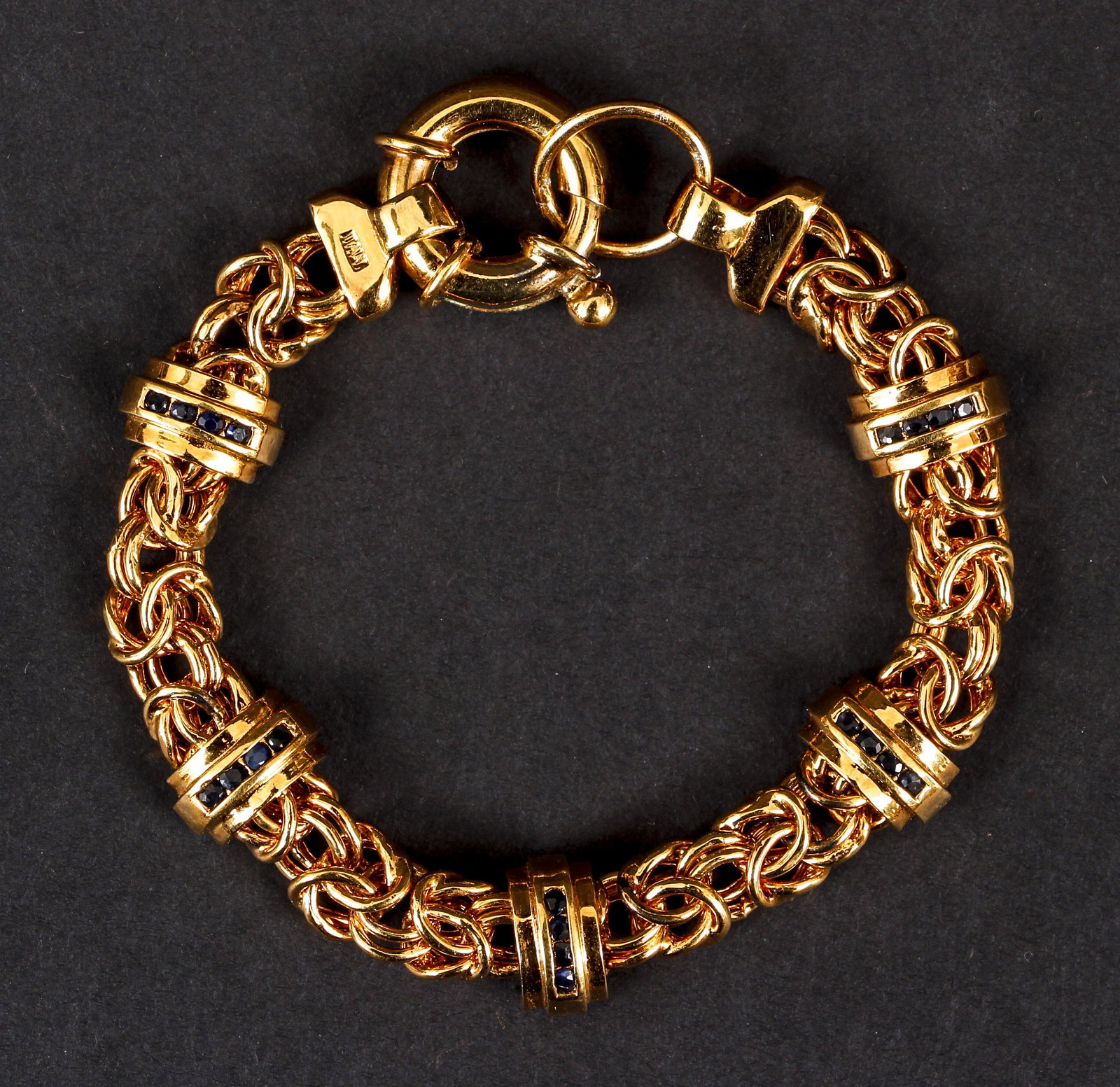 Italian Gold Vermeil Sapphire Bracelet: Italian gold vermeil sapphire bracelet. Fashioned of woven links with 5 attached domed bars set with round cut sapphires. The piece measures 6 1/2" long, 7/16" wide. Finished with a large spring ring 