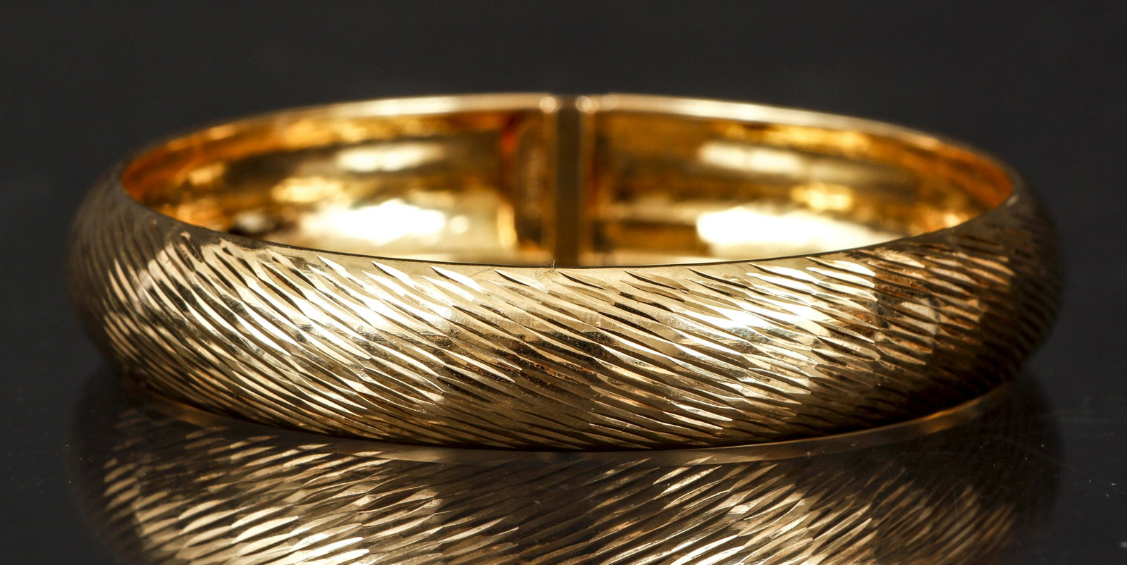Sterling Gold Vermeil Flexible Bangle: Sterling gold vermeil flexible bracelet. The surface of this piece is decorated in a diagonal rough cut engraving. The flexible body closes with a hidden tongue and bar, plus hinged safety clip and ba