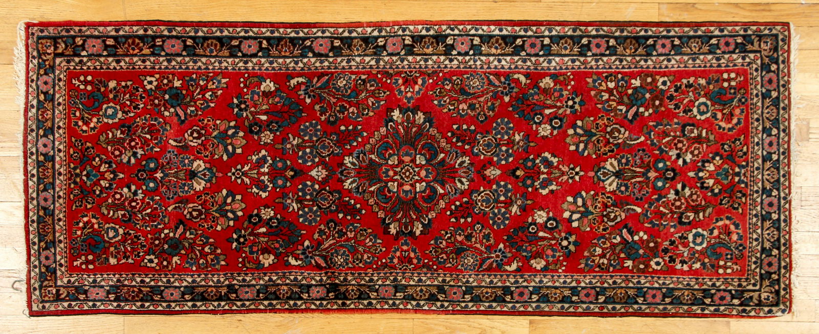 Antique Persian Sarouk Rug: Antique Persian Sarouk Rug with floral motifs against a red ground, 75 x 29 inches.