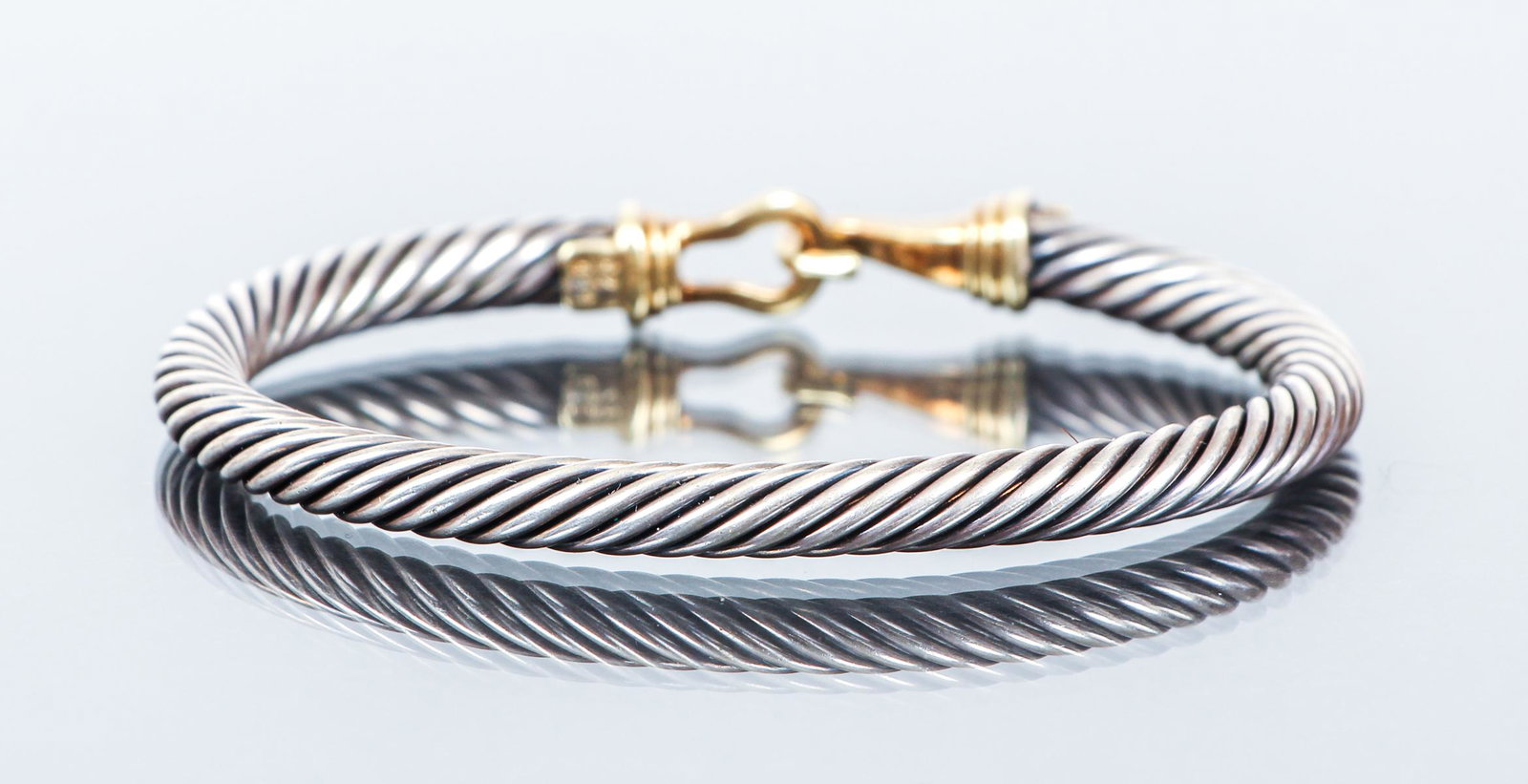 David Yurman 14k and Sterling Cable Bracelet: David Yurman 14k and Sterling cable bracelet, features a hook and eye closure crafted of 14k gold attached to sterling cable band, gold closures are marked "585, 925" on hook side, measures 6 1/8 inch