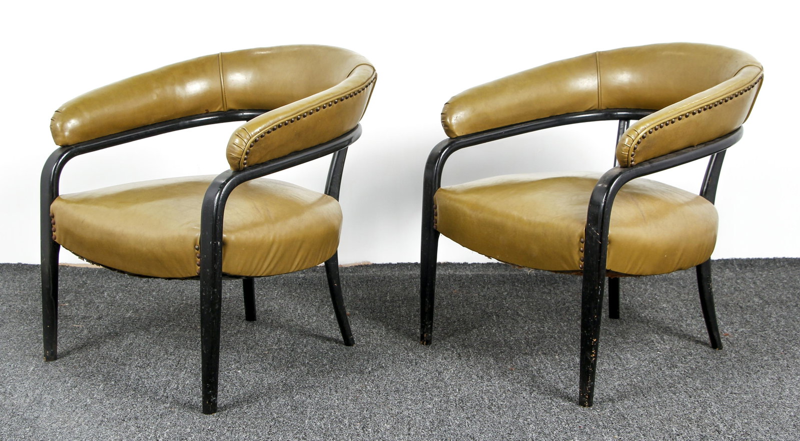 Pair of ebonized and Upholstered Club Chairs: Barrel shaped Club Chairs with Green leather brass tacking, ebonized wood frames, 28 x 27 x 25 inches.