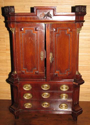 Miniature bench made Mahogany chest on stand: Title: Miniature bench made Mahogany chest on stand with rectangular top, locked center frieze with leaf decoration, flanked by two blocked rosettes and two raised paneled doors, flanked by quarter co