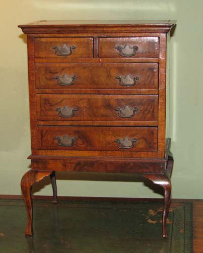 Miniature circassian walnut bench made highboy: Title: Miniature circassian walnut bench made highboy, rectangular cross band top fitted with two short drawers, with brass pulls, over three long drawers, plain skirt, terminated on cabriole legs Med
