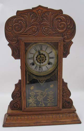 Amherst Clock Waterbury Clock Company: Title: Waterbury oak kitchen clock Medium: oak case with incised and decorated crown Dimensions: 22 x 15 x 4.5 inches Signature: with attached label on reverse Provenance: Amherst Clock Waterbur