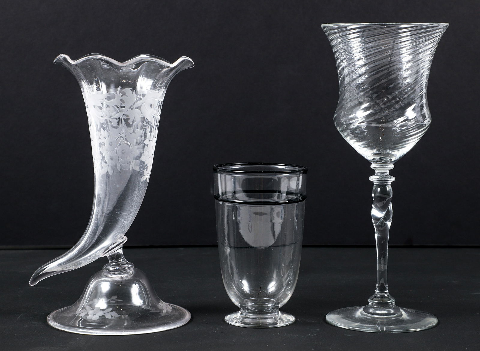 Group of 3 Glassware Pieces Steuben Cornucopia and Goblet: Group of 3 glassware pieces, includes: Footed glass with black line and lip, 4.75 inches tall, Cornucopia vase with floral designed etched onto glass, 8.25 inches tall, Steuben etched to base, and Win