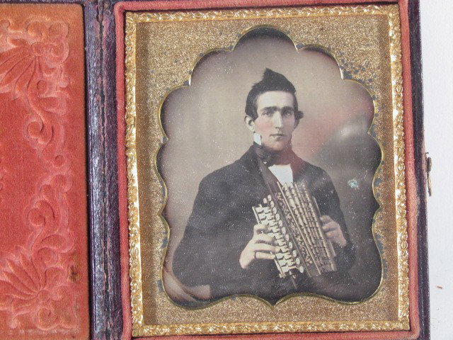 Pair Musician Daguerreotype and Ambrotype: Title: Lot of two sixth plate musicians with squeezebox accordions and hand painted rosy cheeks Medium: 1 daguerreotype, 1 ambrotype Dimensions: 3.25 x 2.75 inches Frame Type: brown leather cases Fram