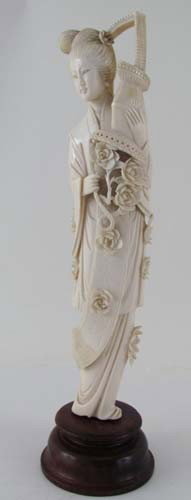 Ivory Okimono of a standing woman with robe with c: Title: Ivory tusk carving Okimono of woman with basket with roses Medium: ivory figurine on wooden stand Dimensions: 9.25 x 2 x 1.5 inches Signature: seal on lower back side in red