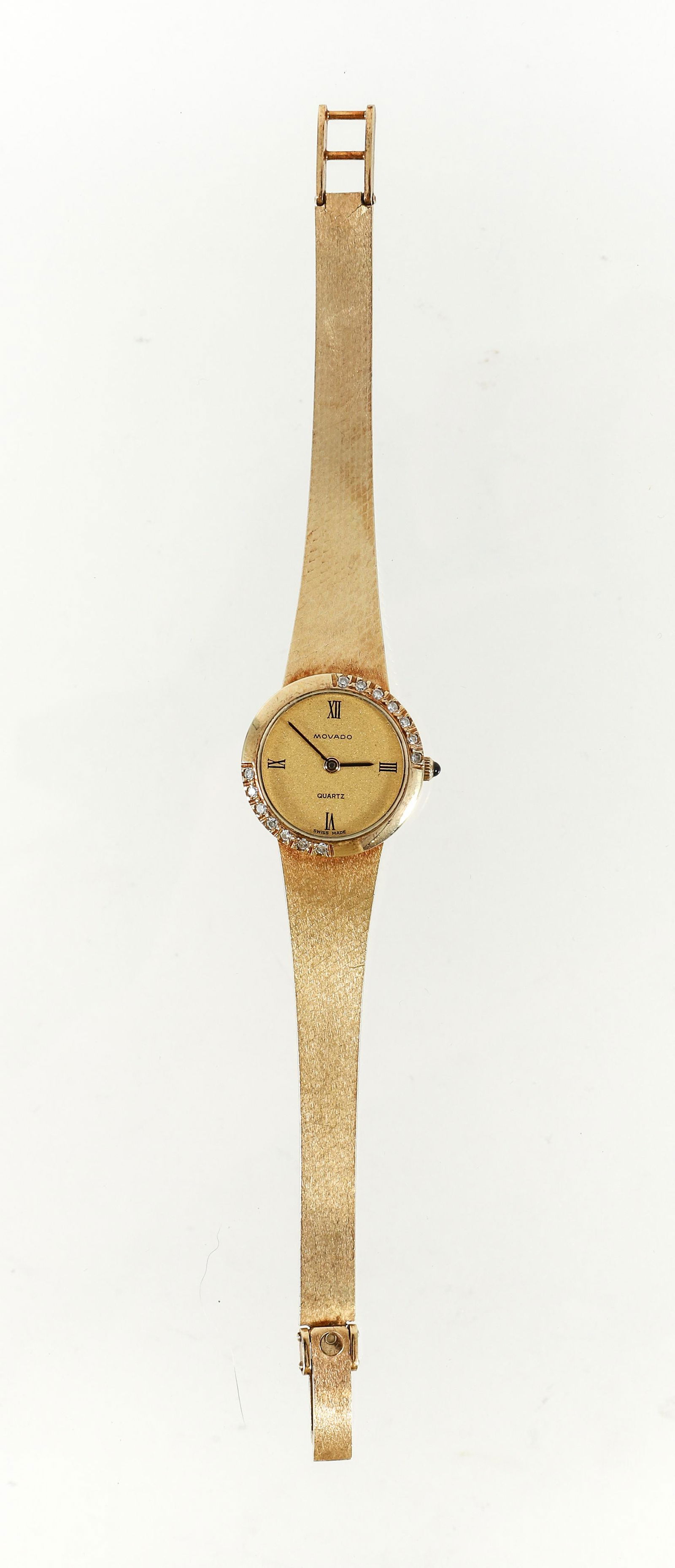 Womens 14K Diamond Movado Quartz Wristwatch: Womens 14K yellow gold Movado diamond quartz wristwatch. The 14K yellow watch face is marked with Roman numerals at the quarter hour. Measures 11/16" diam. Marked "Movado Quartz Swiss Made". Gold case